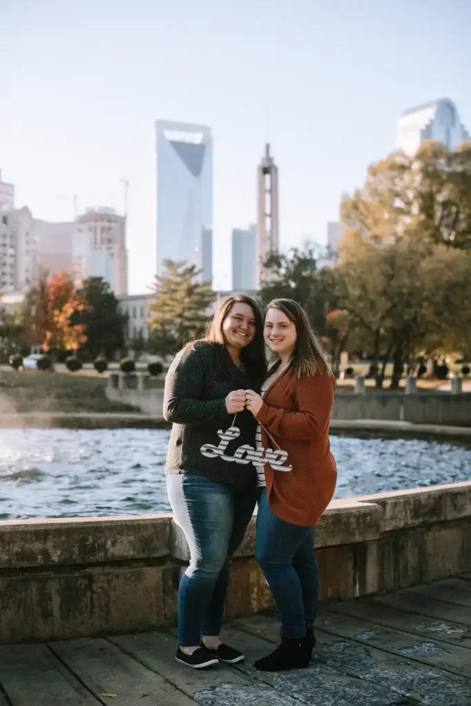 A couple poses in front of a fountain at Marshall Park during their engagement photography session in Charlotte, NC