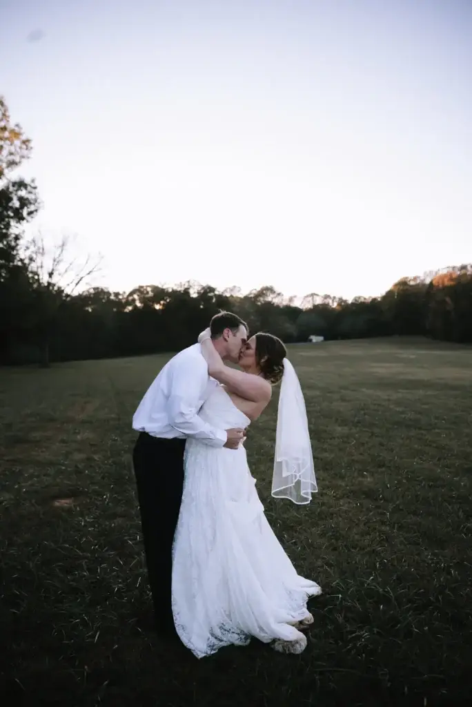 A couple kisses close to sunset after their wedding at Red Barn Events in Waxhaw, NC as shot by Charlotte wedding photographer Claudia Wolff