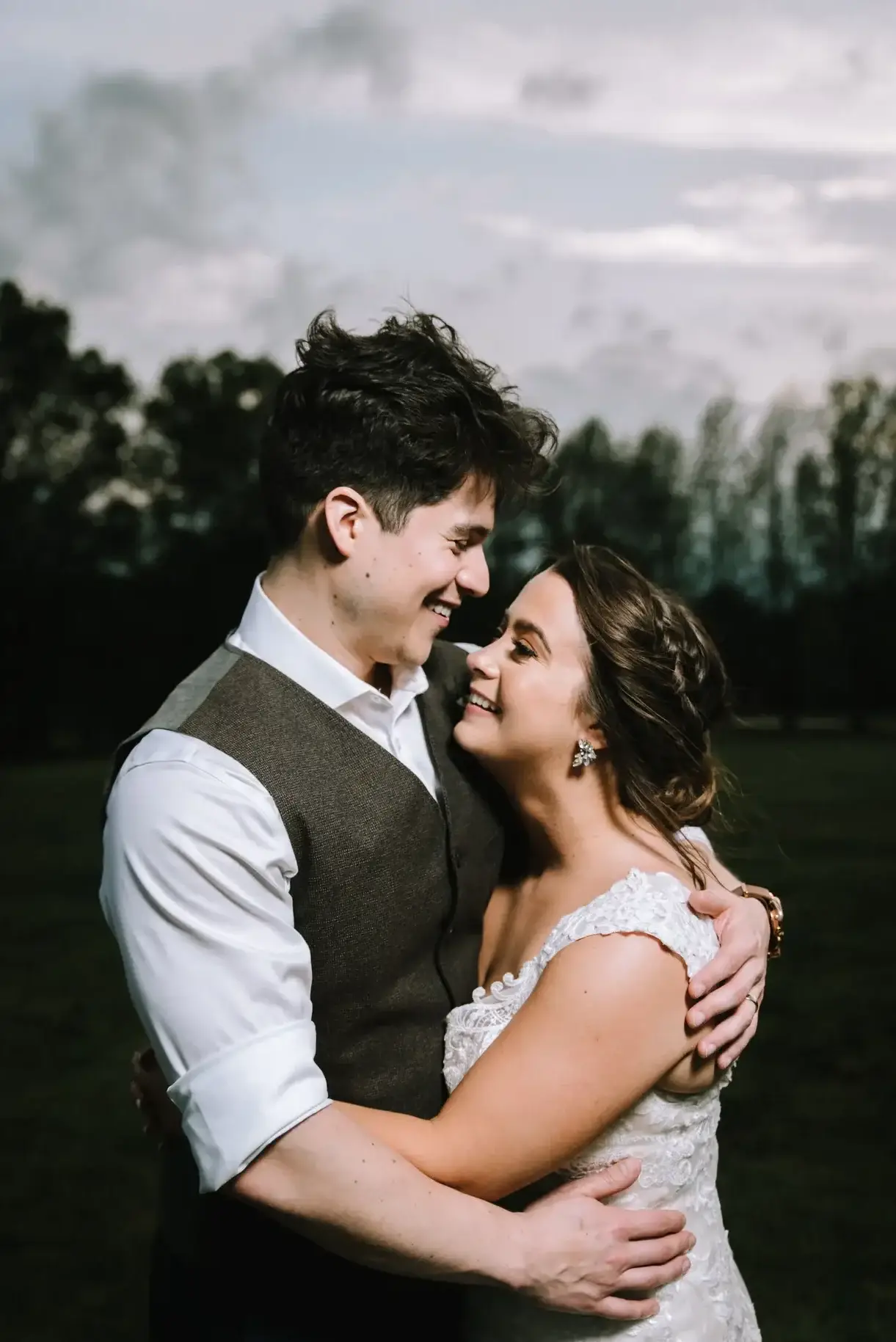 A couple smiles as the sun finishes setting after their wedding at the Field Trial Barn at Anne Springs Close Greenway in Fort Mill, SC.