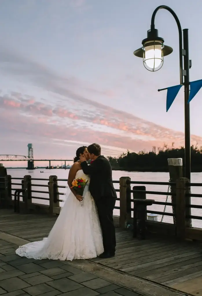 A couple kiss during sunset photos in downtown Wilmington, NC as shot by Charlotte wedding photographer Claudia Wolff